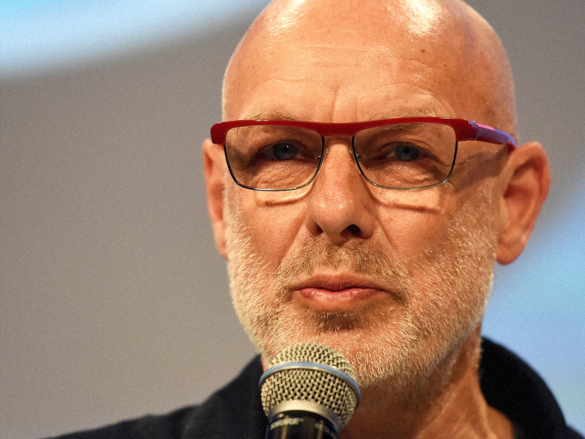 Brian Eno speaks into a microphone
