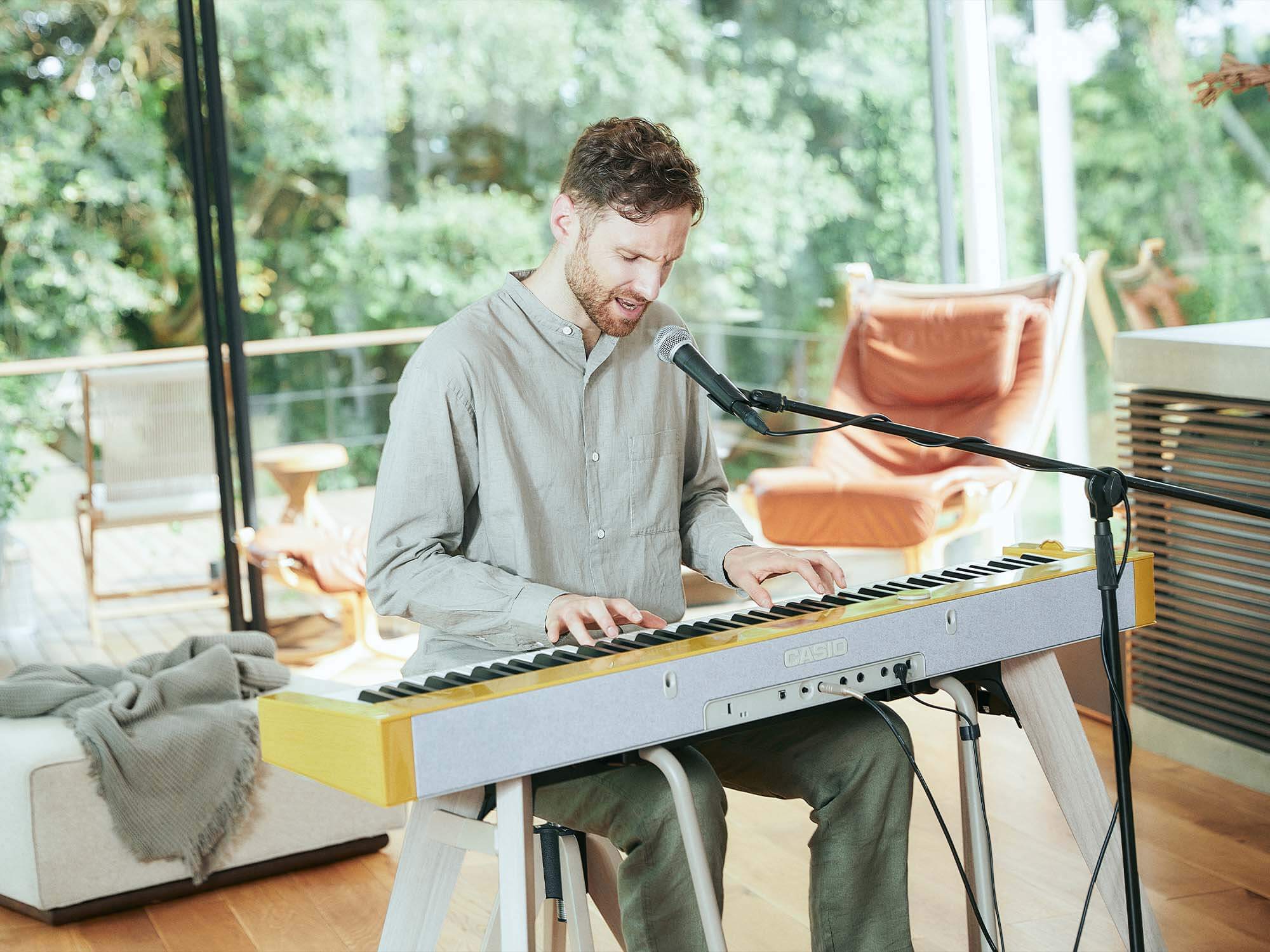 Man in grey shirt plays casio PX-S7000 in home with microphone