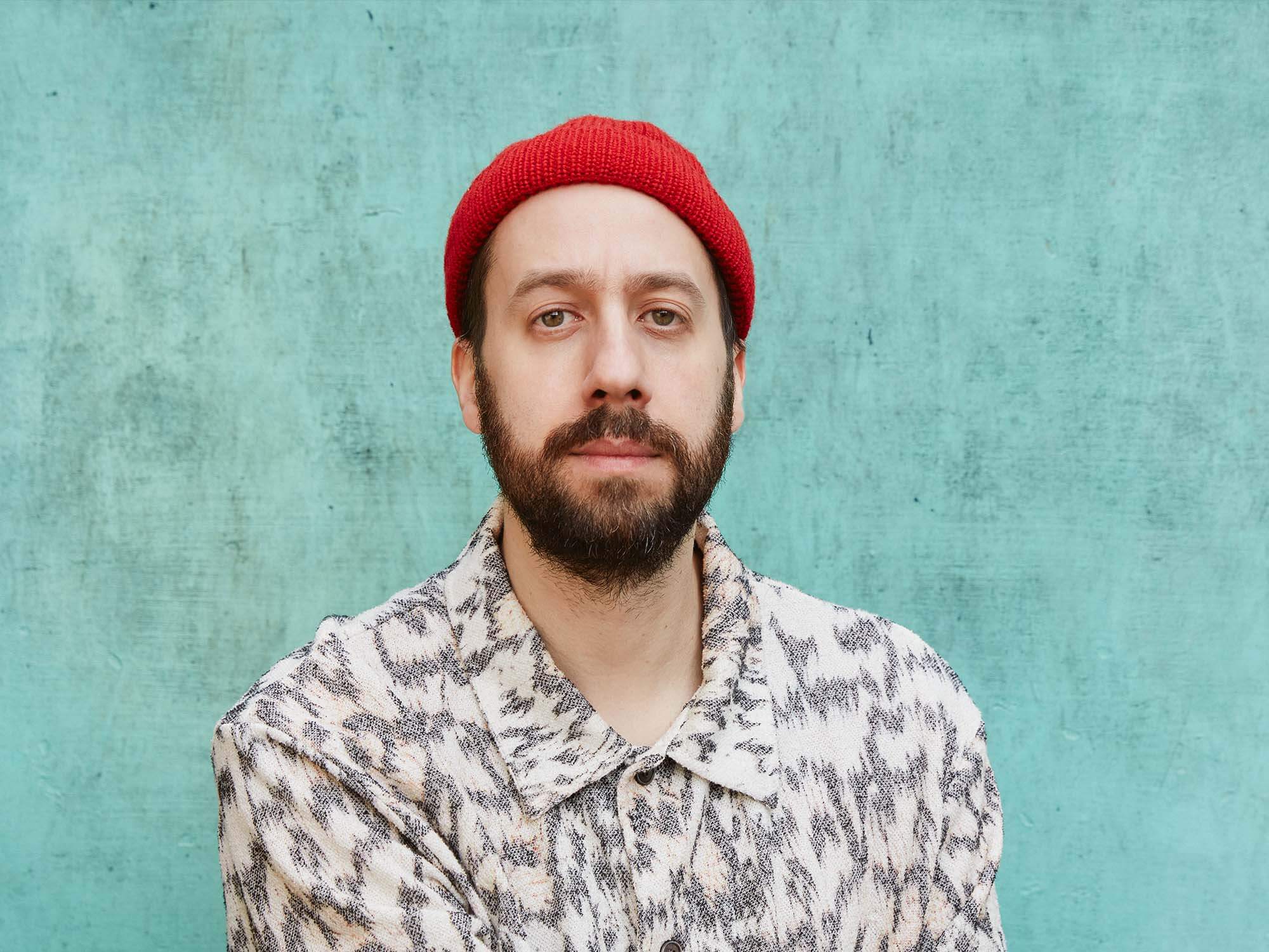 Gold Panda wearing red hat with blue background