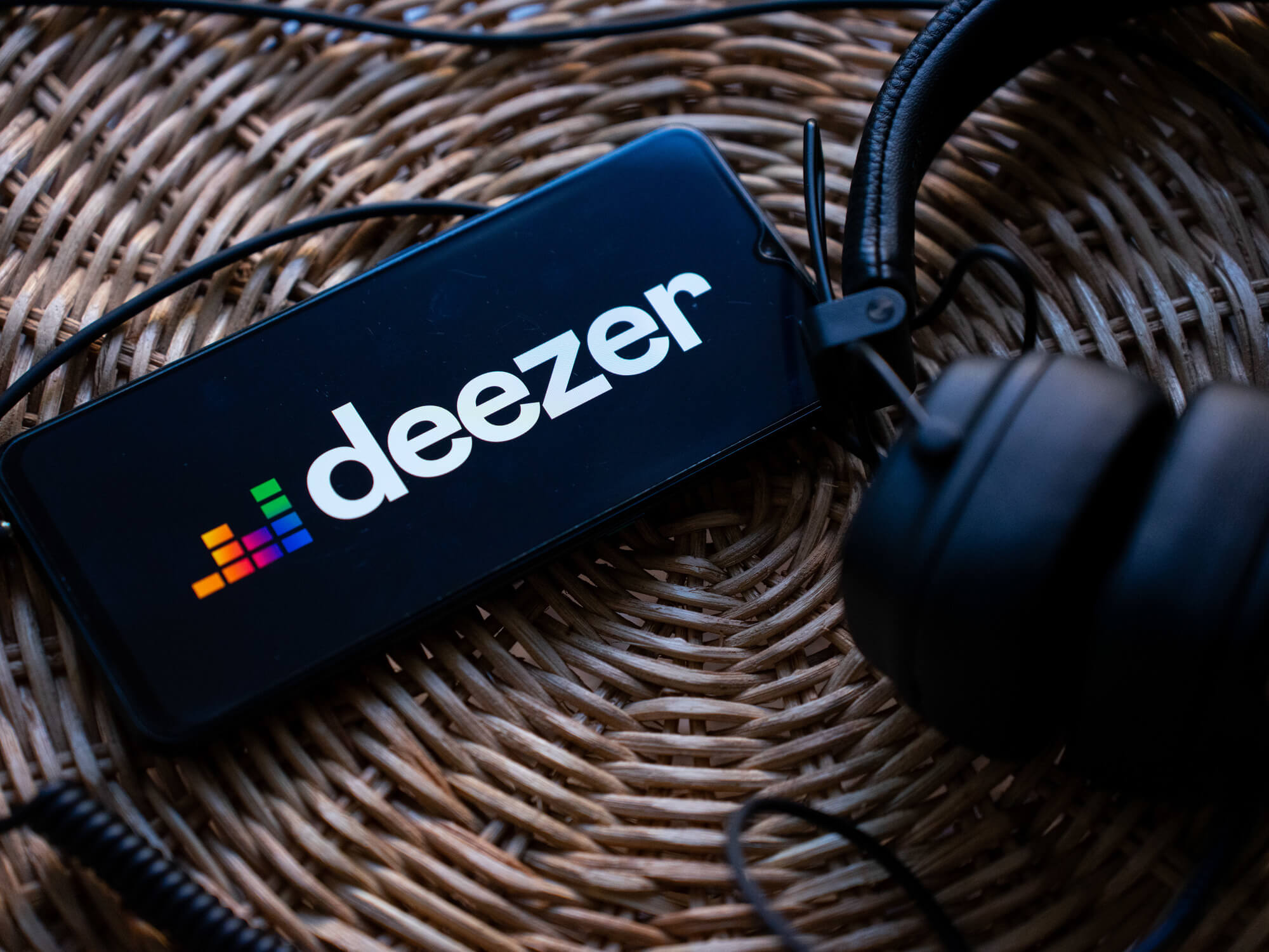 The Deezer logo on smartphone next to a pair of headphones