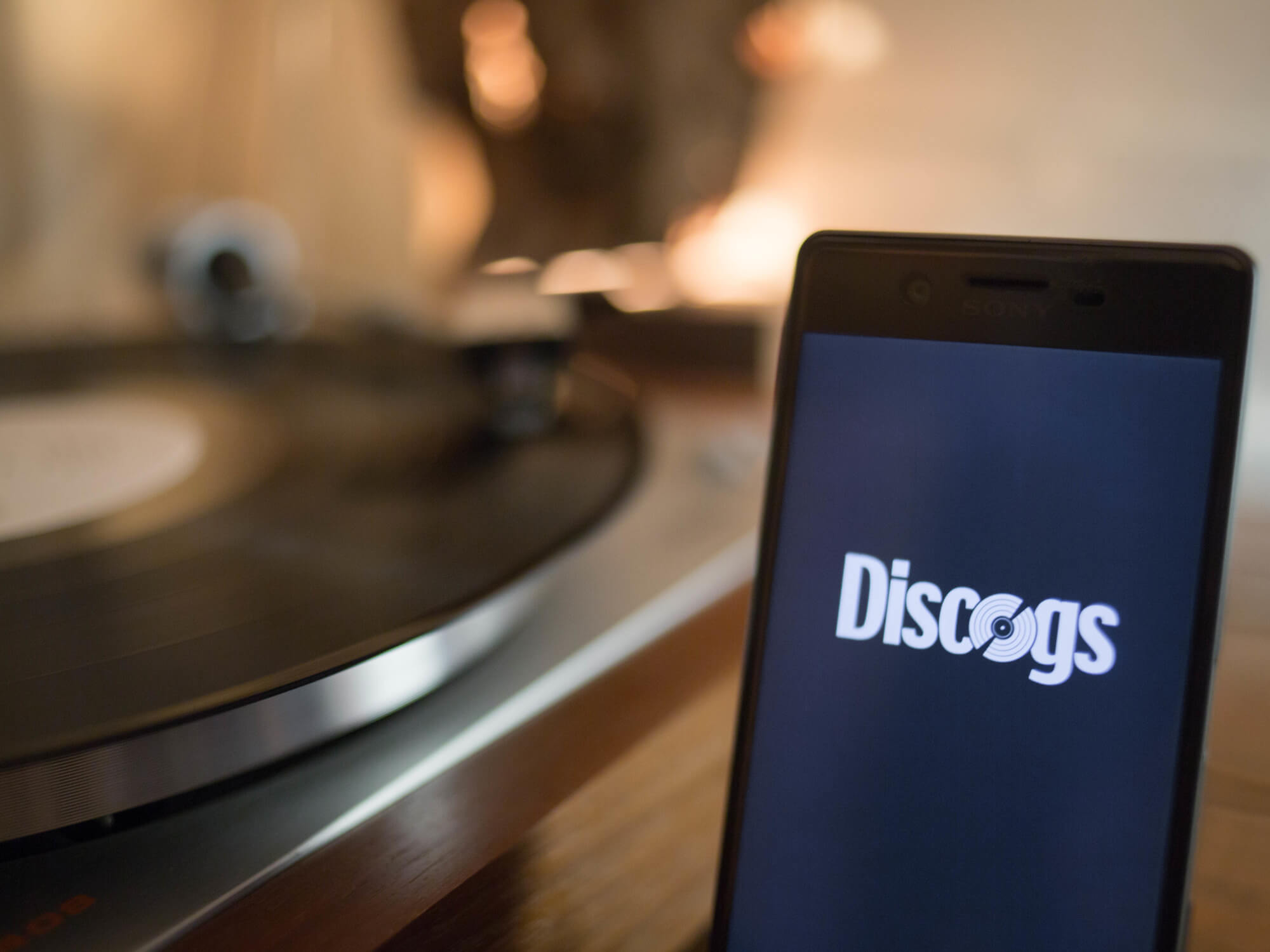 Discogs logo on smartphone next to record player
