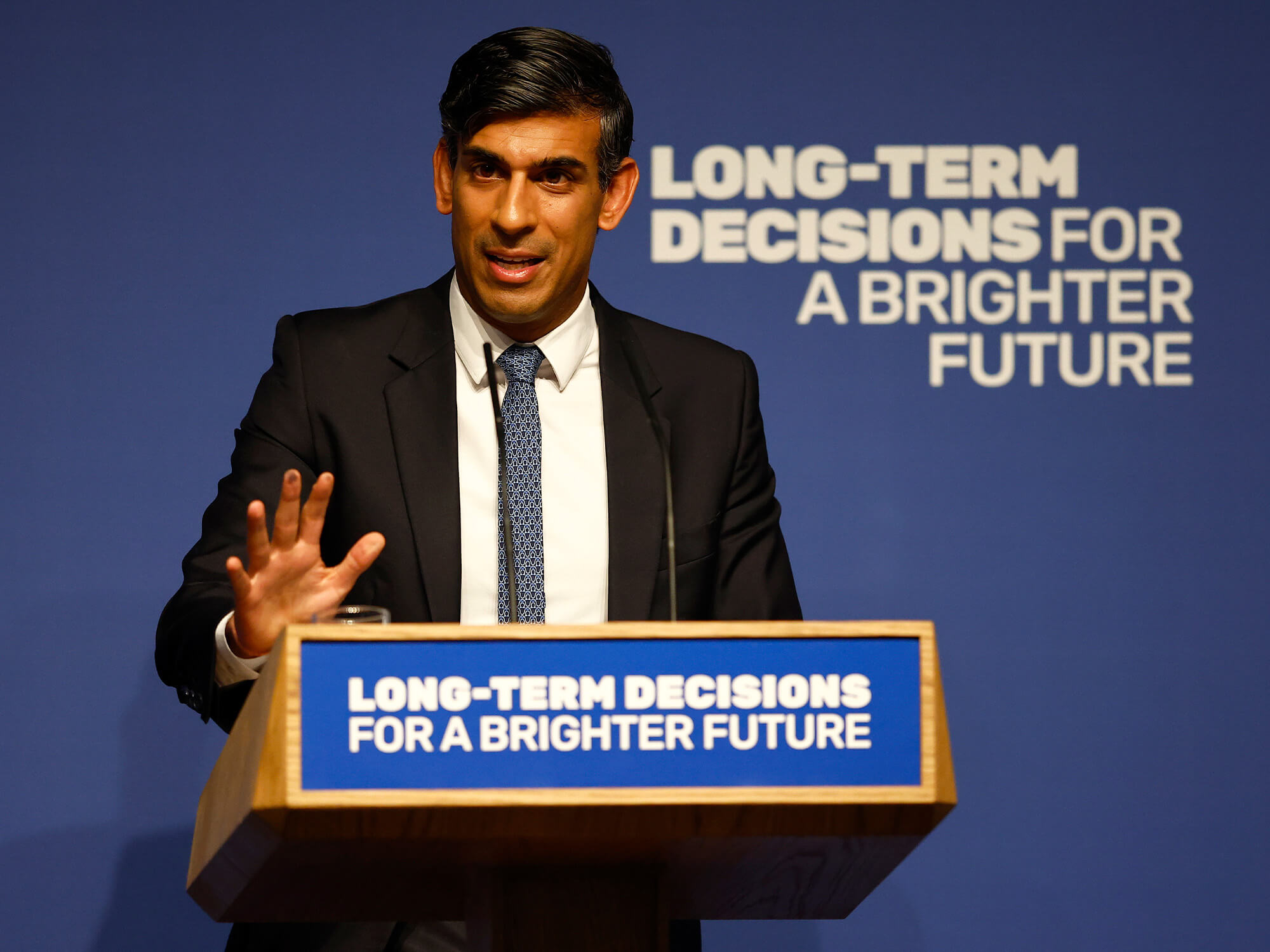UK Prime Minister Rishi Sunak stood behind a podium that reads "long-term decisions for a brighter future"