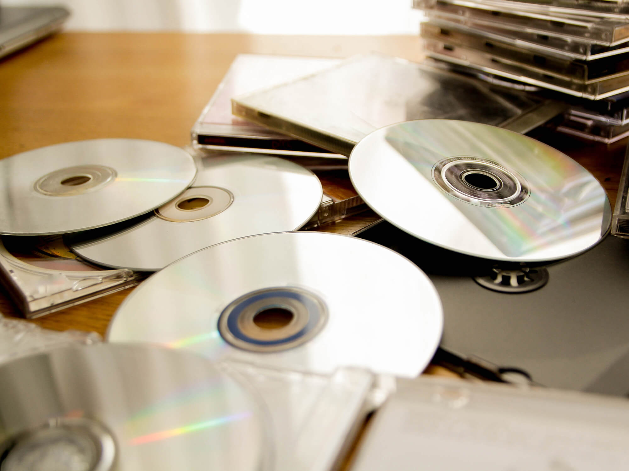 CDs spread out on a table among a stack of plastic CD cases