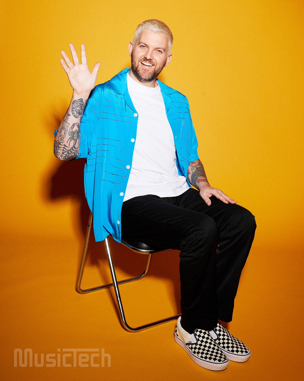 Dillon Francis sitting on a chair and waving, photo by Clare Gillen
