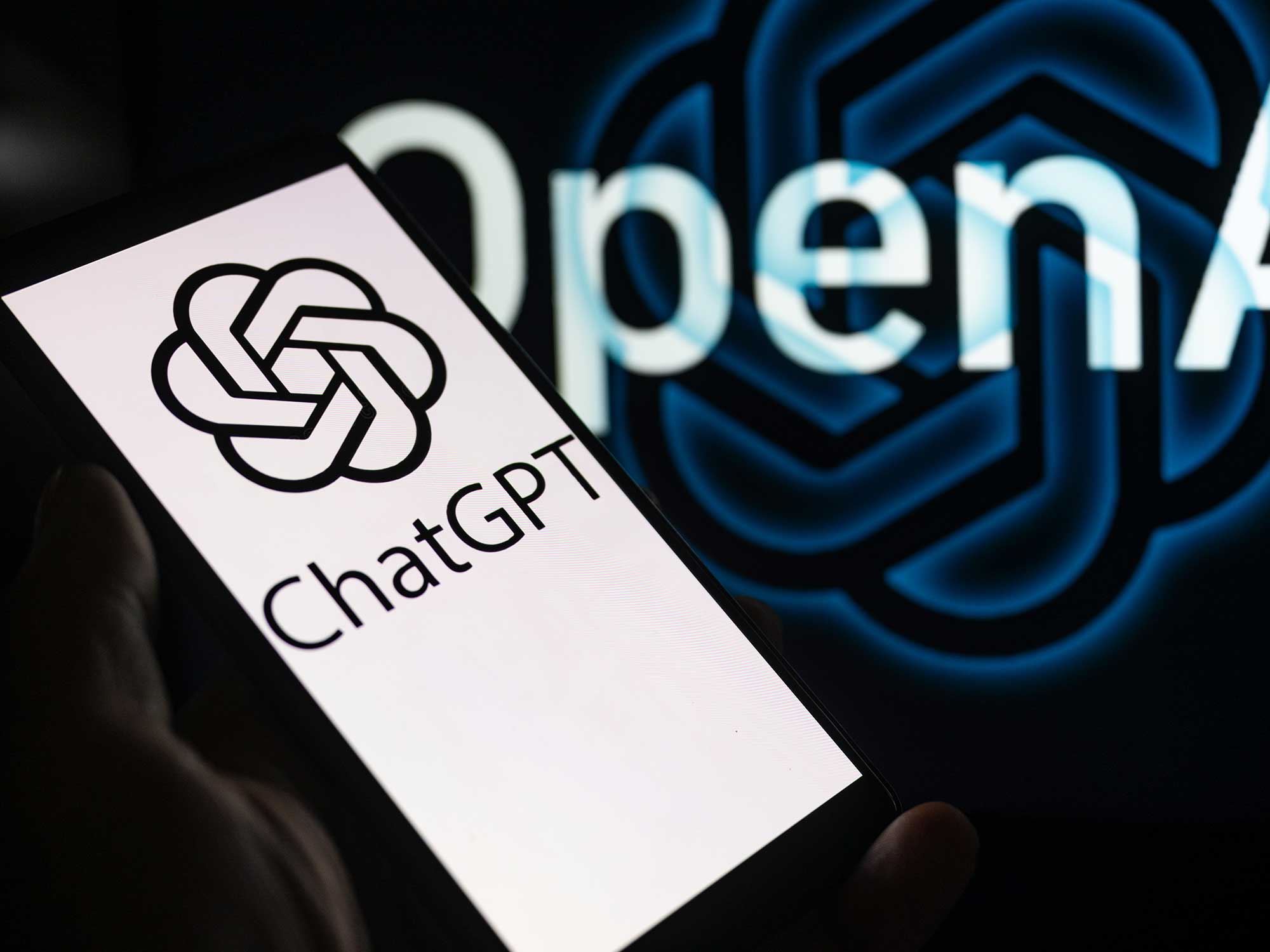 A smartphone displaying ChatGPT with the OpenAI logo in the background is being shown in this photo illustration in Brussels, Belgium, on December 3, 2023.