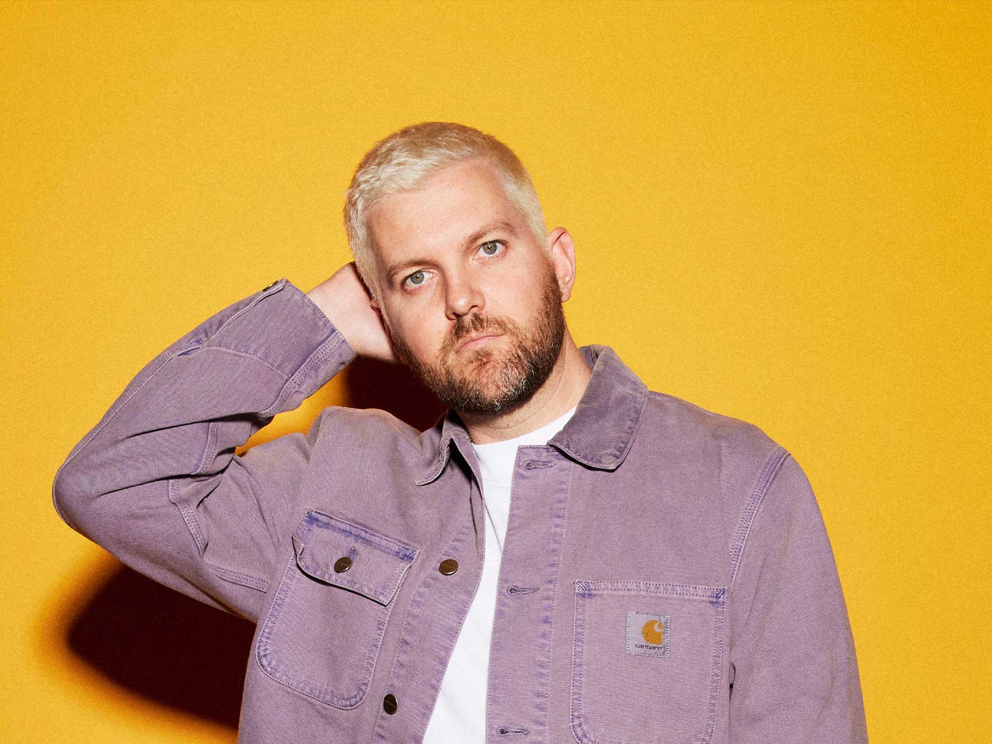 Dillon Francis in front of a sunset orange background