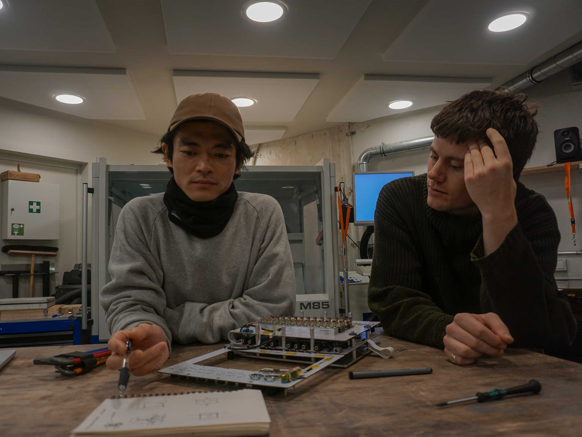 Lukas Haartman and Tatsuya Takahashi in their synth workshop making notes