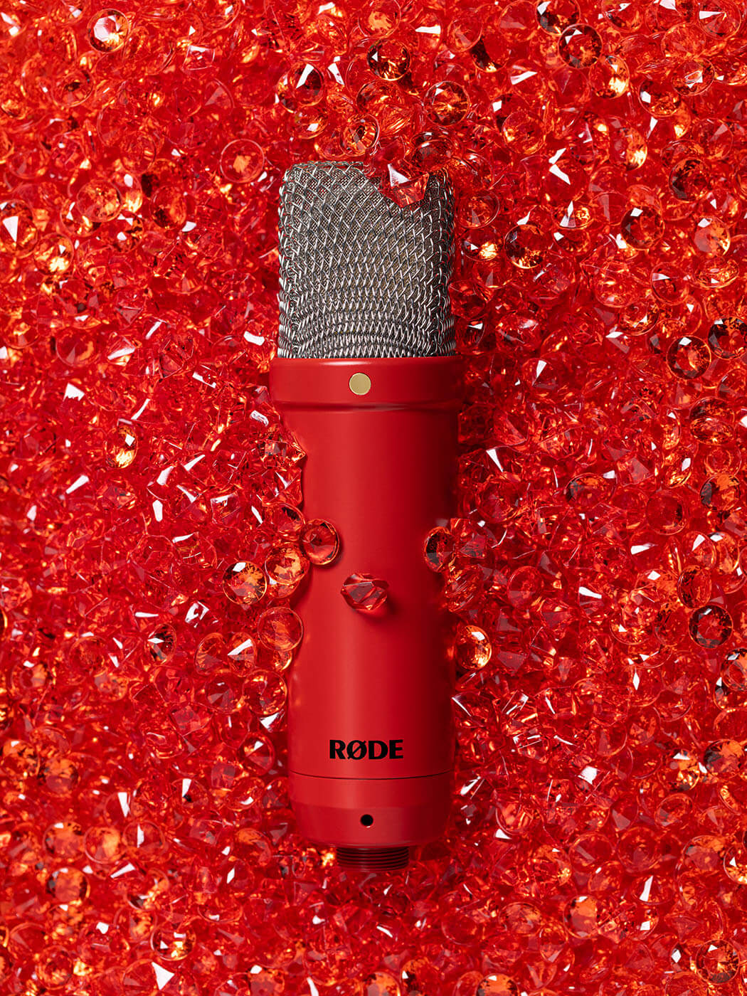 RØDE NT1 Signature Series condenser microphone in red, photographed against a background of red jewels