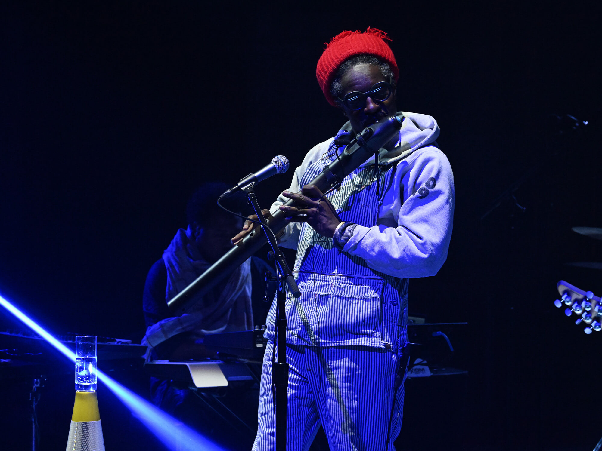 Andre 3000 on stage. He is playing a woodwind instrument.