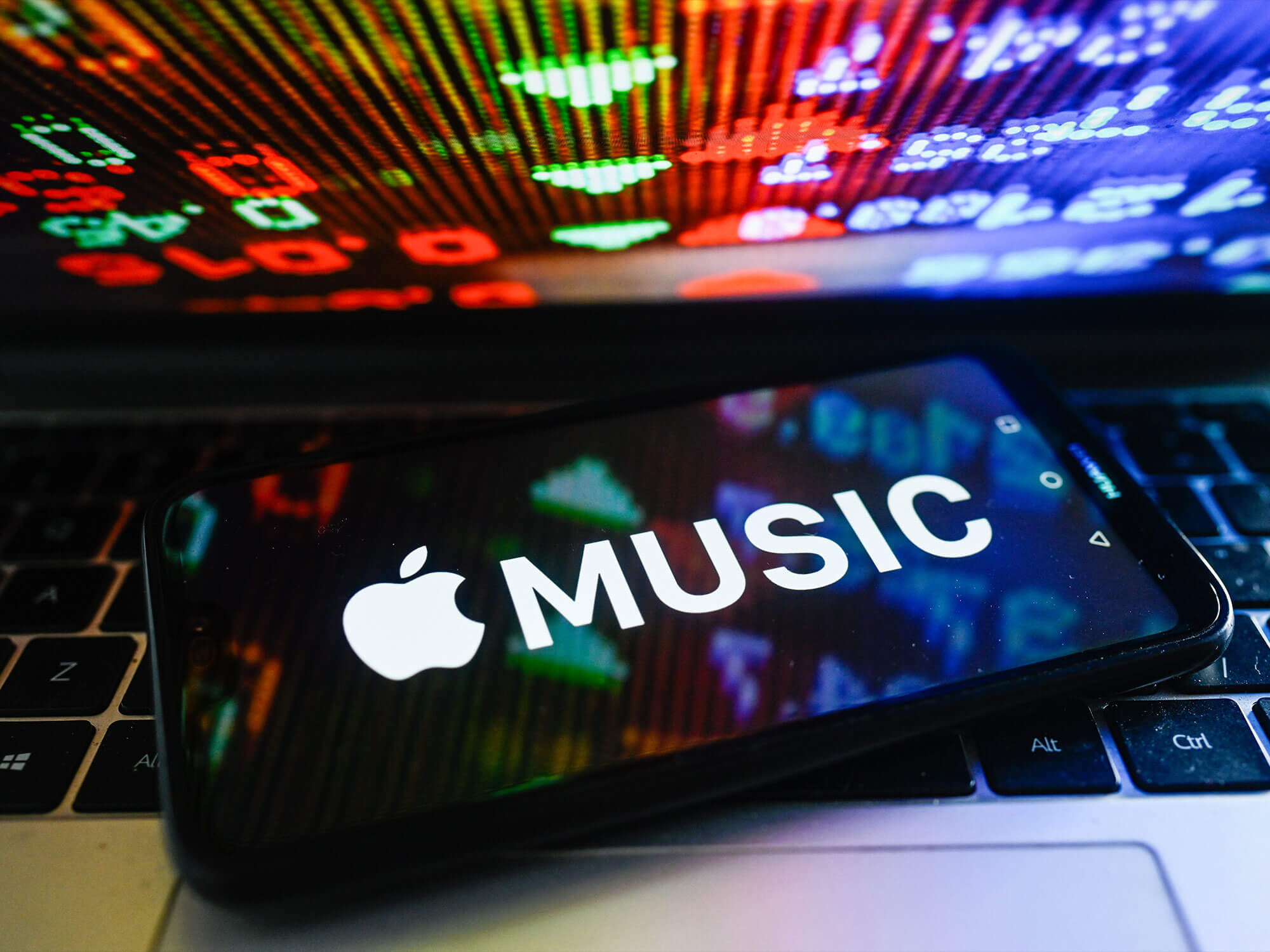 Apple Music logo on a phone, which is on a laptop keyboard