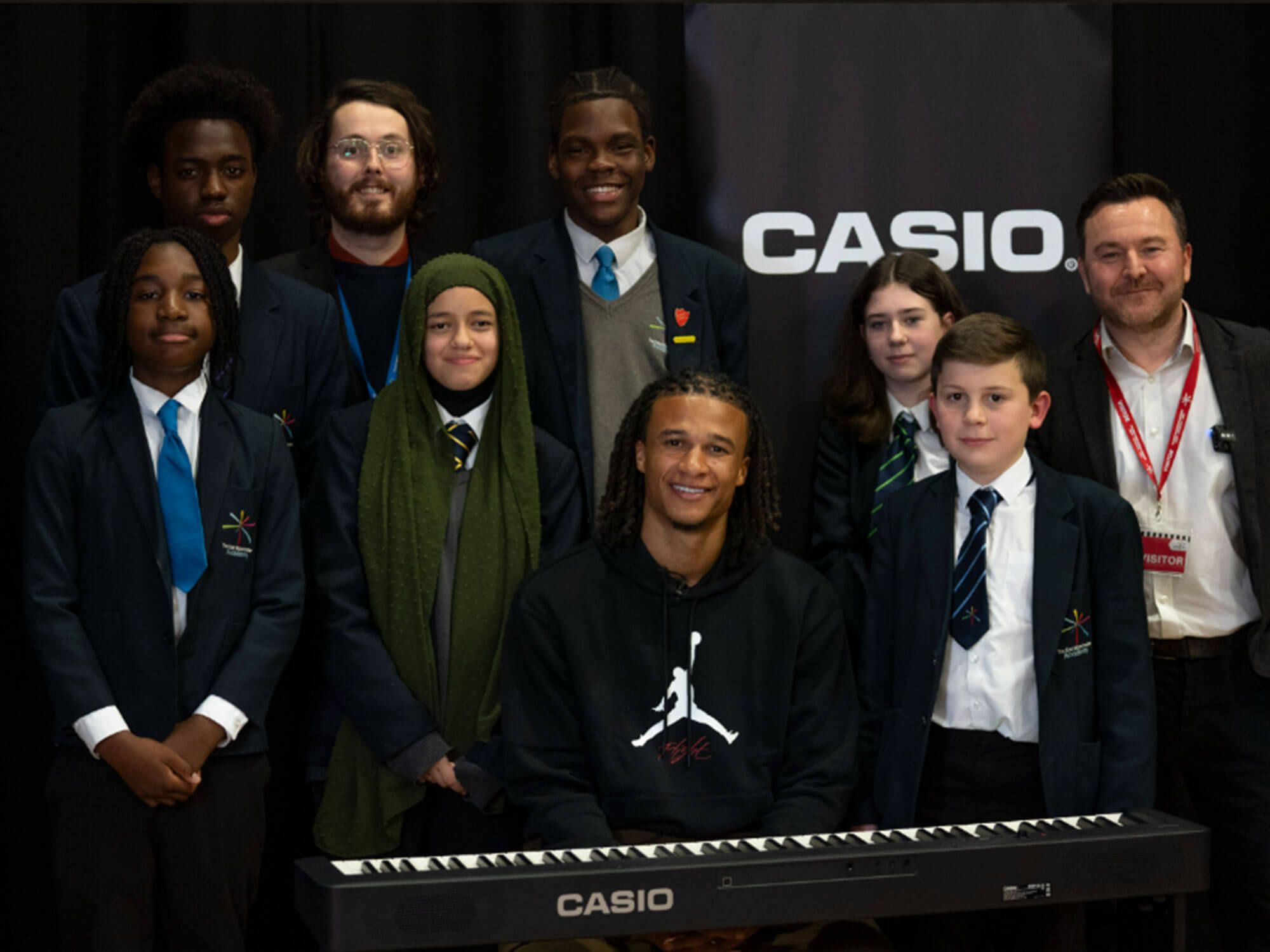 Nathan Aké at a piano with schoolchildren
