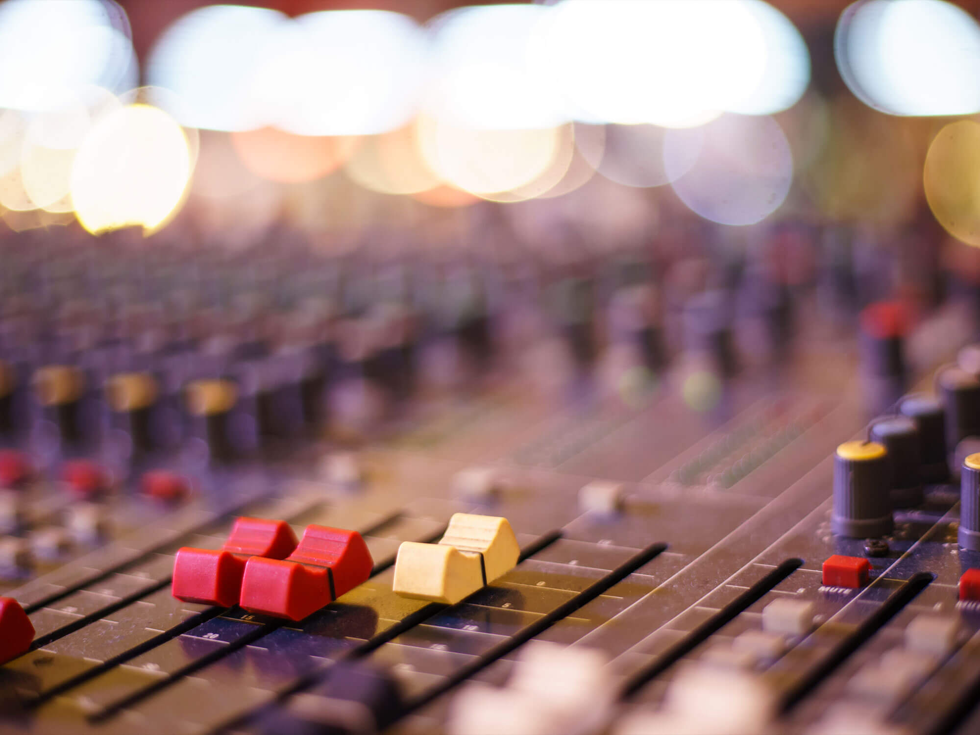 Image of faders on a mixing desk in a music studio