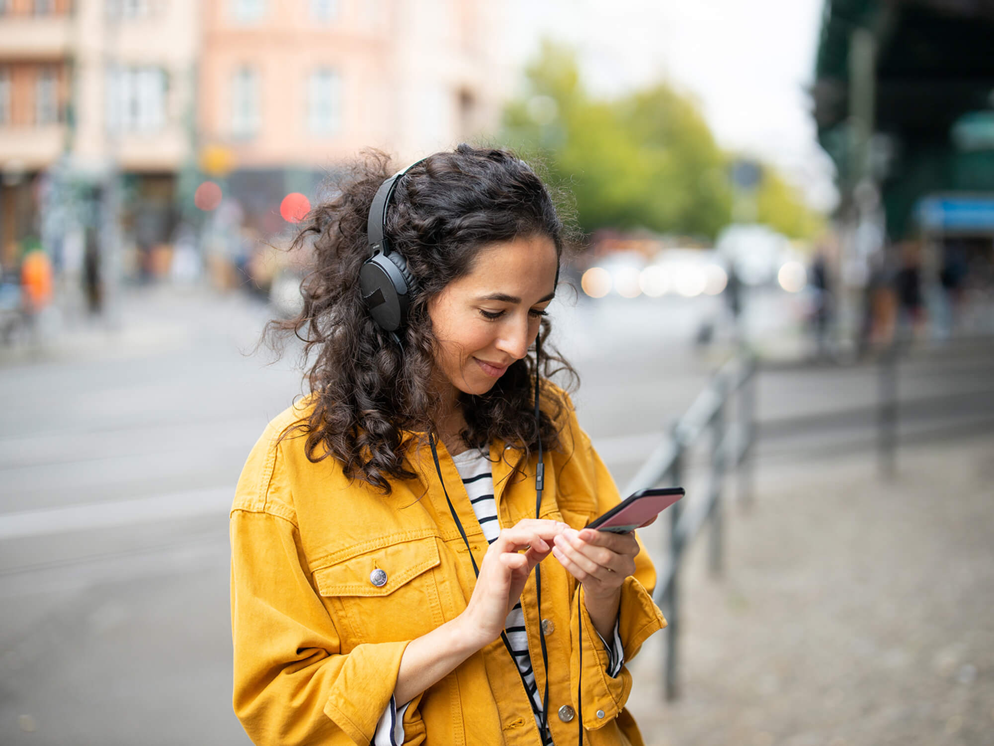 Woman listening to music with headphones in a city, photo by Luis Alvarez/Getty Images