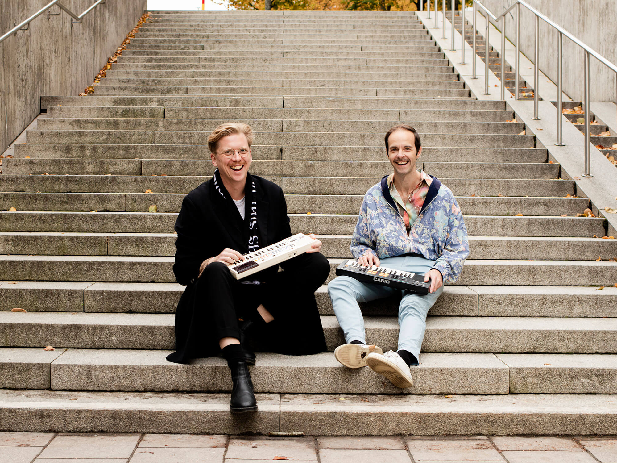 Forever 89's Svante Stadler and Rikard Jönsson sat on stairs holding classic synthesizers
