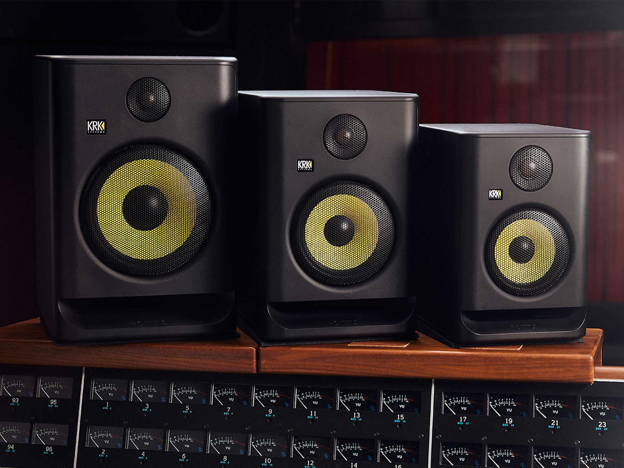 The KRK Rockit Gen 5 speakers. They are lined up in size order, and are black with yellow coloured speakers.