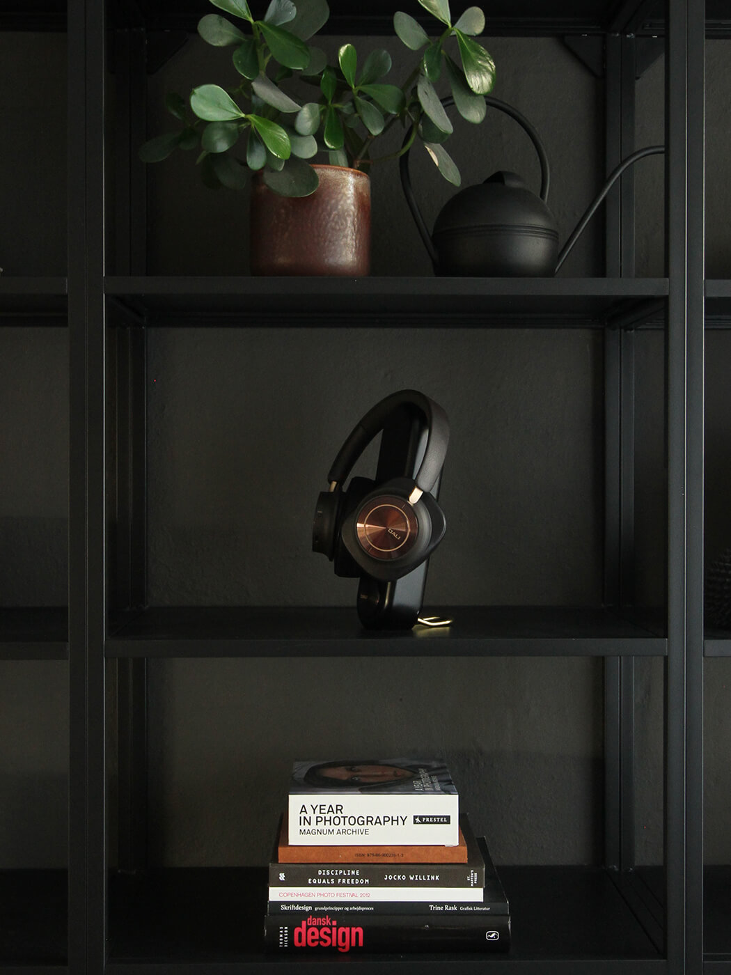 DALI IO-12 headphones on a stand displayed on a shelf