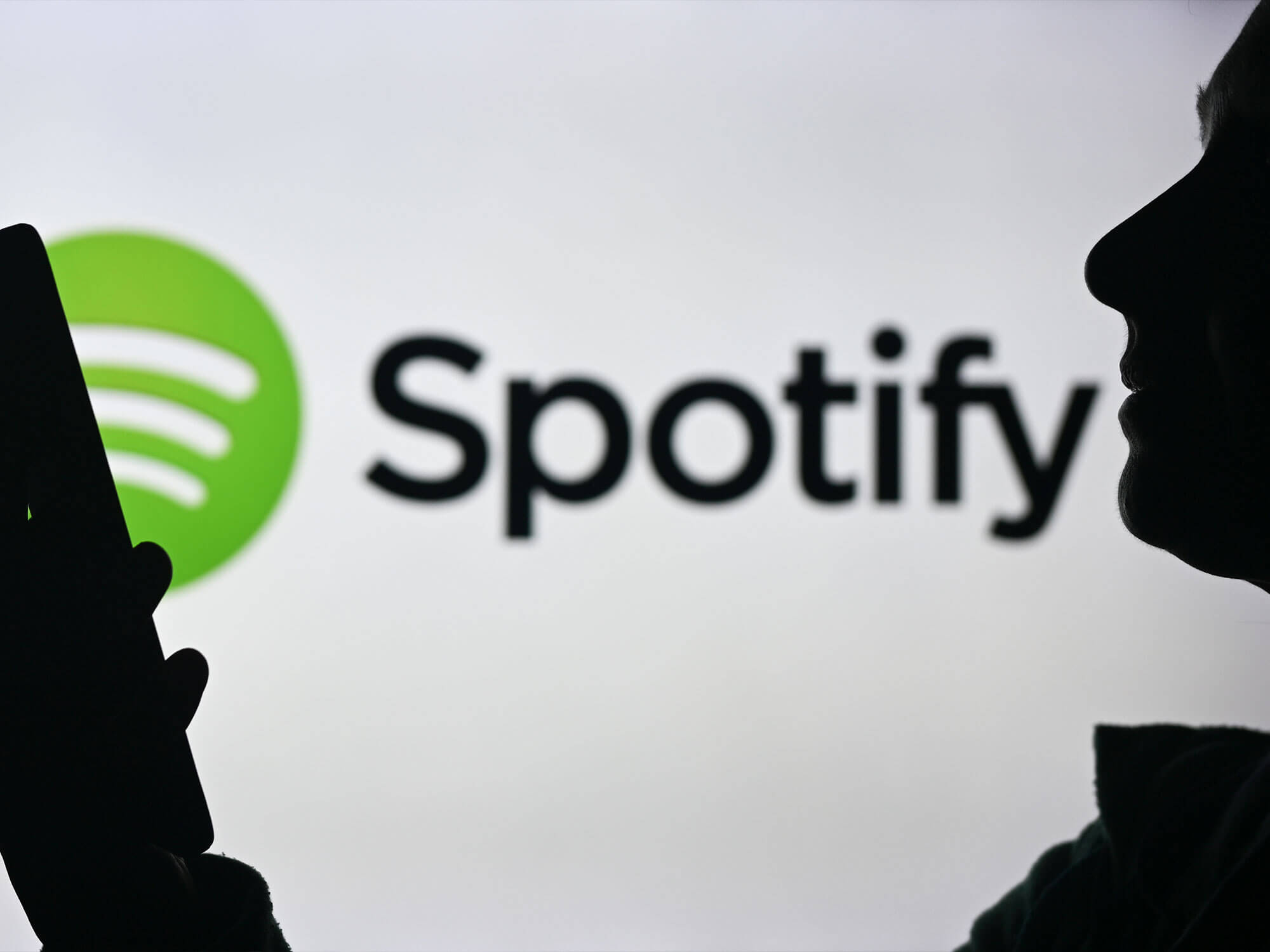 Spotify logo with a woman holding a smartphone
