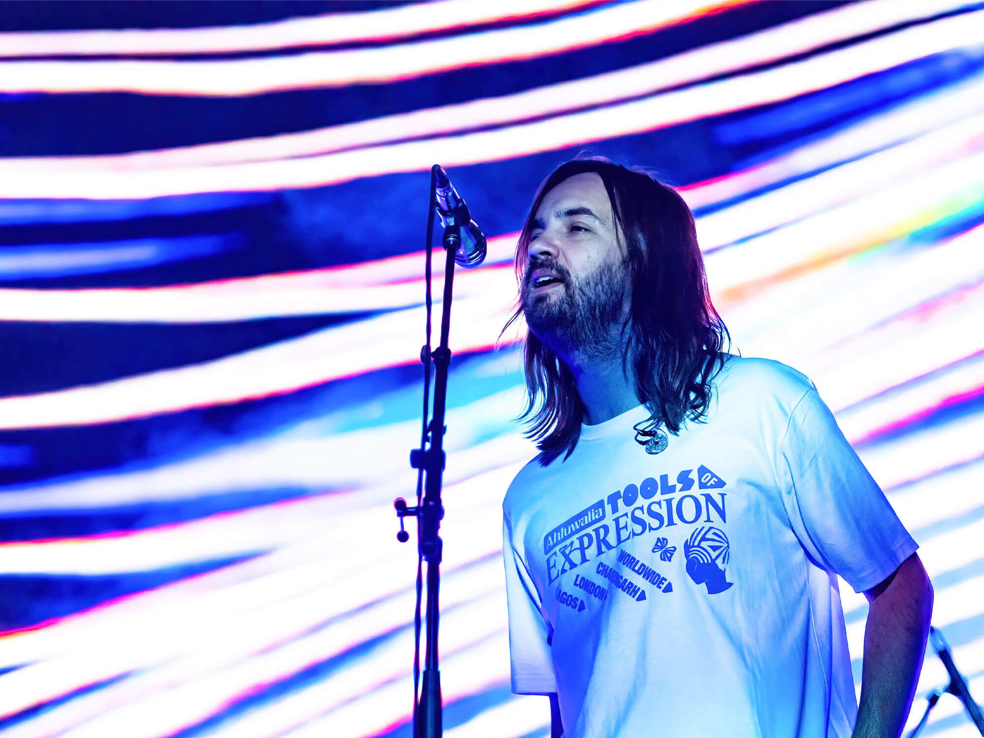 Tame Impala (Kevin Parker) on stage singing into a mic.